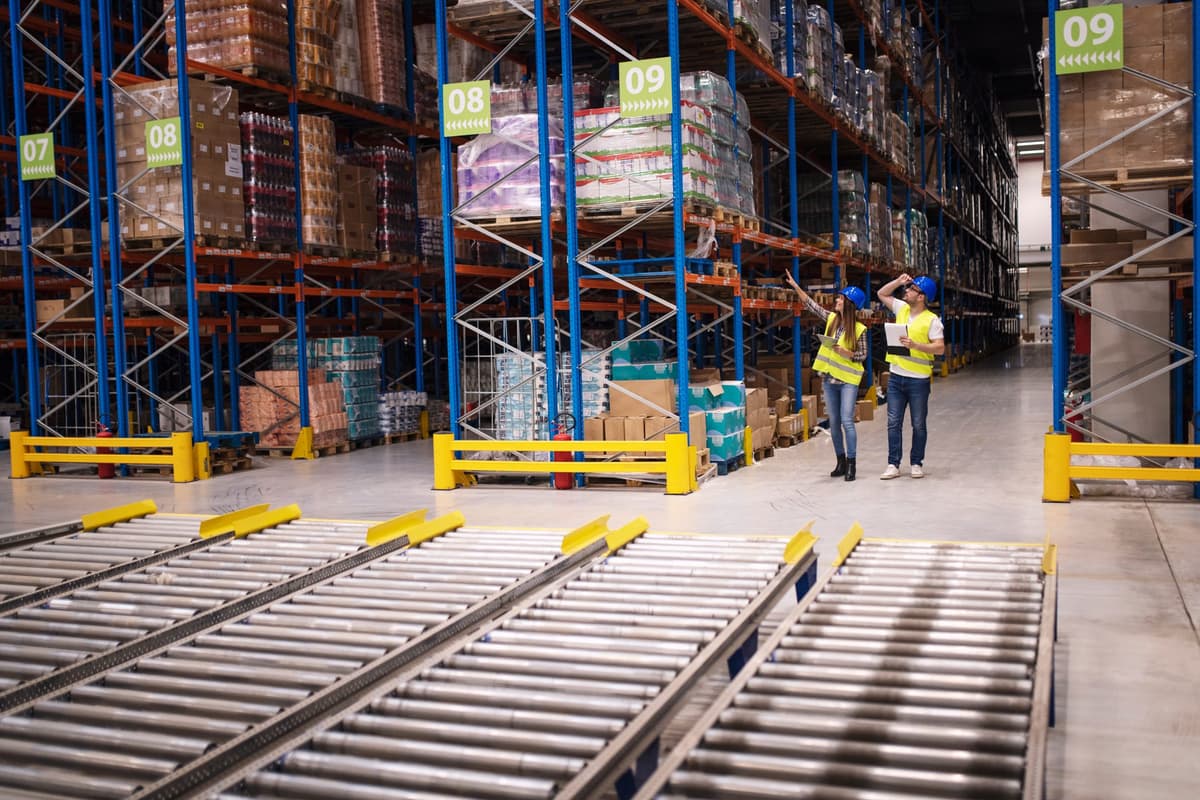 Workers in a warehouse with tall shelving